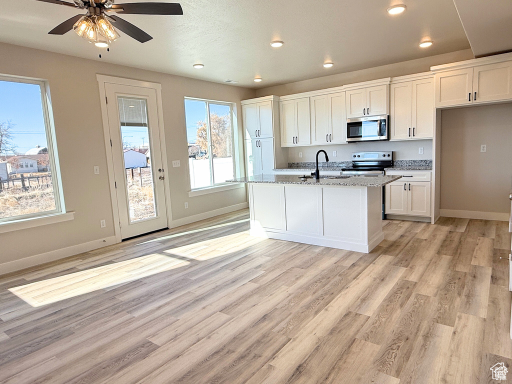 Kitchen featuring appliances with stainless steel finishes, a sink, white cabinetry, baseboards, and recessed lighting