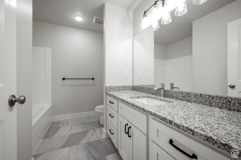 Bathroom featuring toilet, marble finish flooring, baseboards, and vanity
