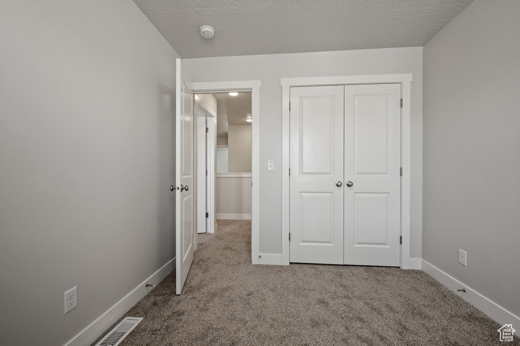 Unfurnished bedroom with carpet flooring, a closet, and baseboards