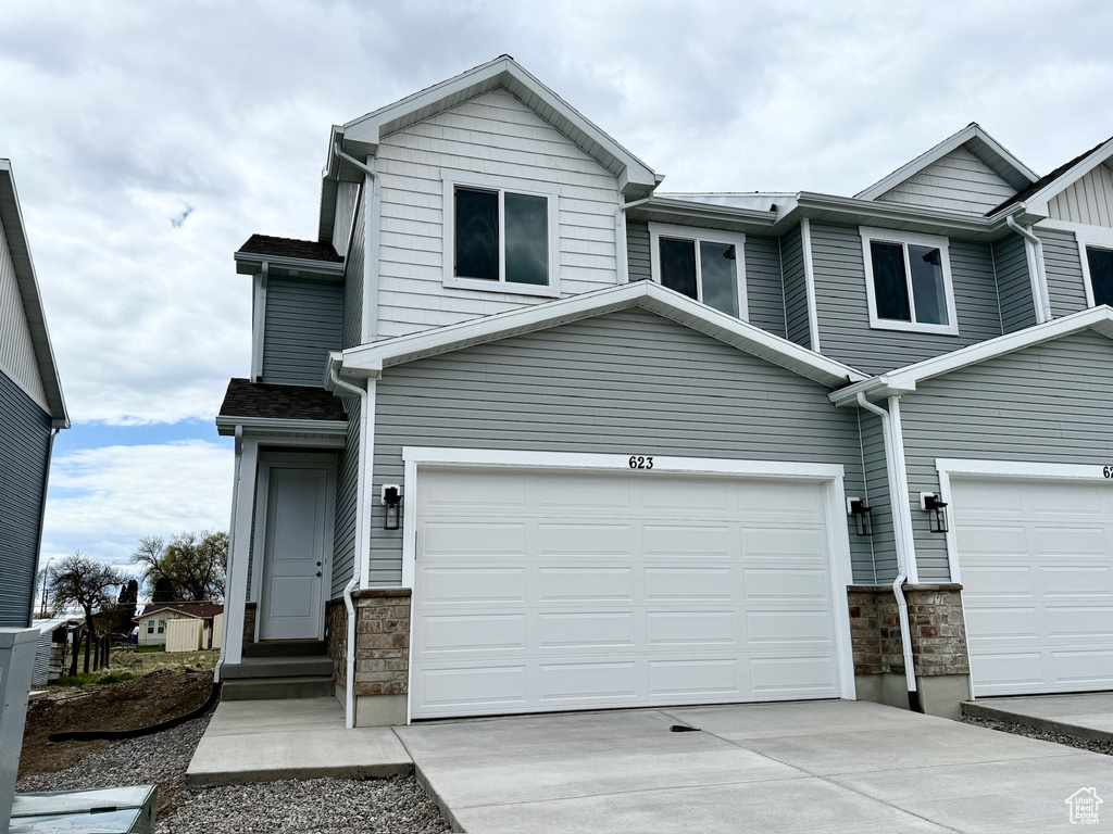View of property with stone siding, concrete driveway, and an attached garage