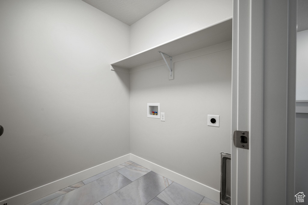Laundry room with hookup for a washing machine, baseboards, hookup for an electric dryer, and light marble finish flooring