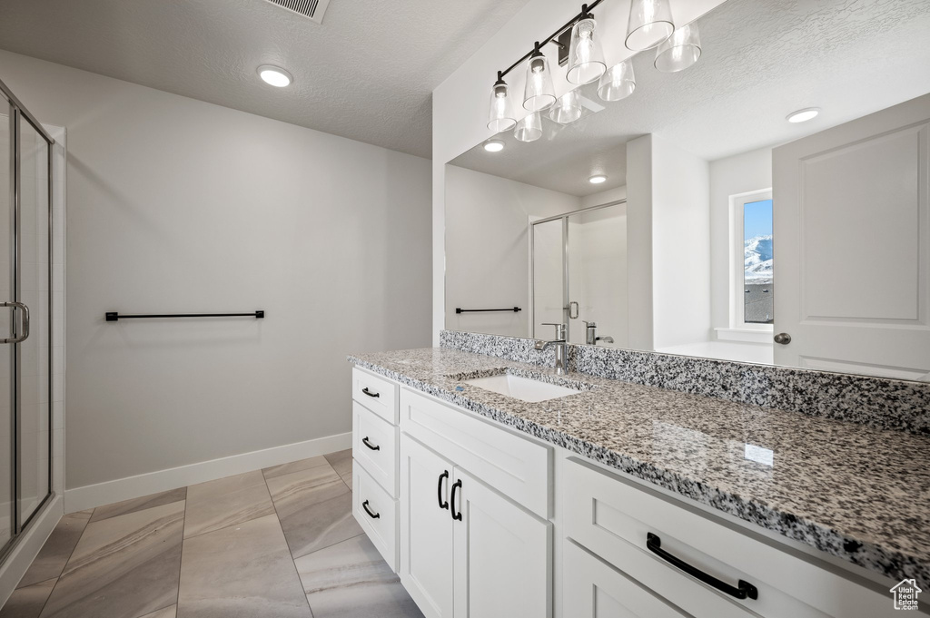 Full bath featuring baseboards, a stall shower, vanity, marble finish floors, and a textured ceiling