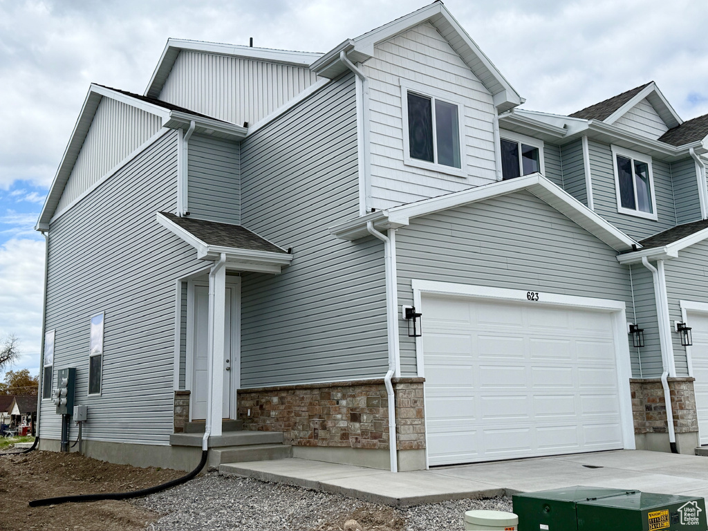 View of side of property featuring stone siding, an attached garage, and driveway