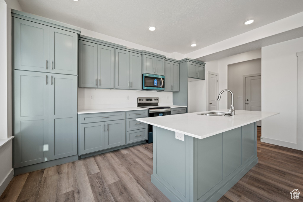 Kitchen featuring appliances with stainless steel finishes, a sink, dark wood-style flooring, recessed lighting, and light countertops