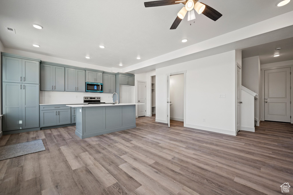 Kitchen featuring stainless steel appliances, recessed lighting, light countertops, light wood-style flooring, and a ceiling fan