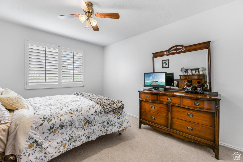 Bedroom with light carpet, baseboards, and a ceiling fan