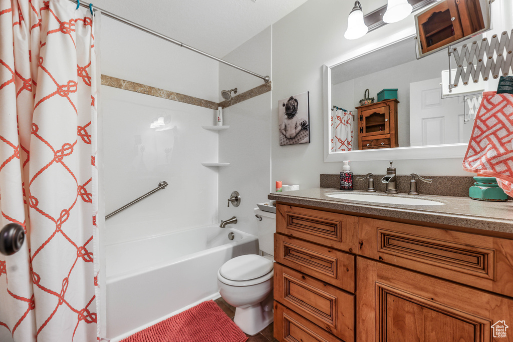 Bathroom with toilet, shower / tub combo, and vanity