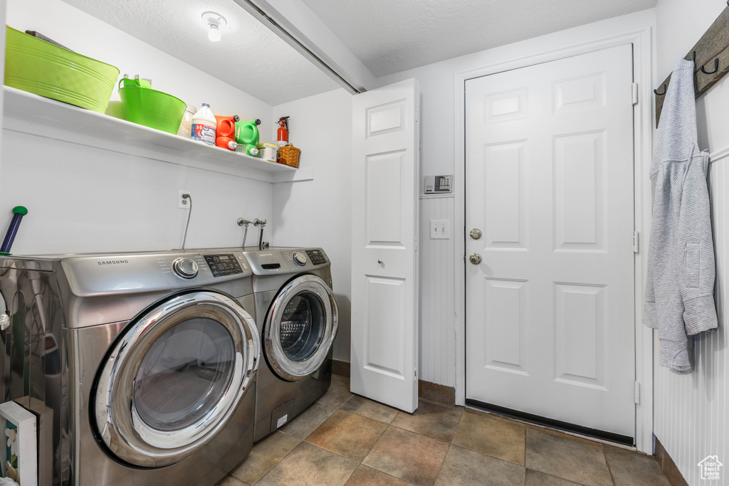 Clothes washing area featuring laundry area, baseboards, separate washer and dryer, and stone finish flooring
