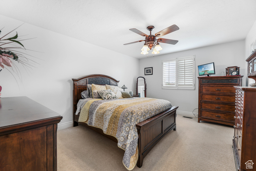 Bedroom featuring baseboards, a ceiling fan, and light colored carpet