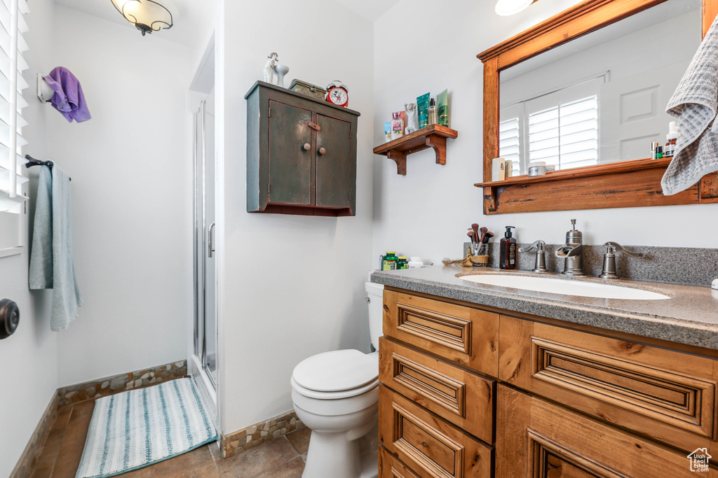 Bathroom featuring vanity, toilet, baseboards, and a stall shower