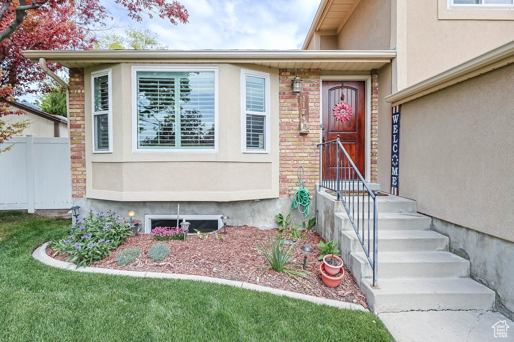 Doorway to property featuring stucco siding and fence