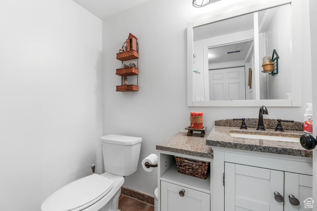 Bathroom with toilet, baseboards, tile patterned floors, and vanity