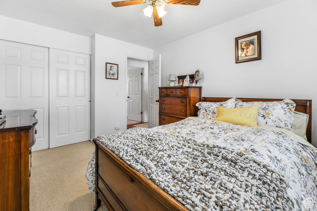 Bedroom with light carpet, a closet, and ceiling fan