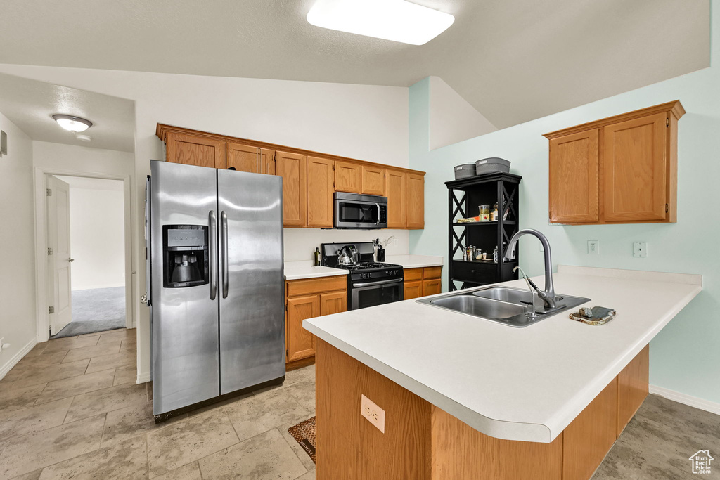 Kitchen featuring appliances with stainless steel finishes, a sink, a peninsula, light countertops, and baseboards