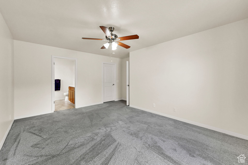 Carpeted empty room with ceiling fan and baseboards