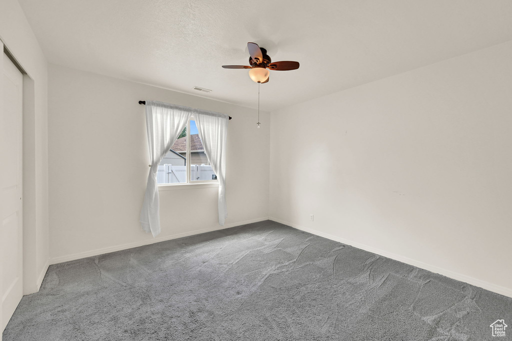 Carpeted spare room featuring a ceiling fan and baseboards