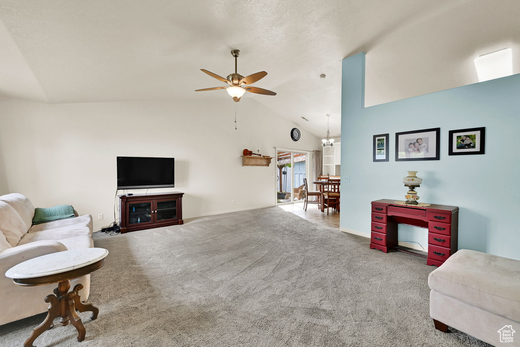 Carpeted living room with vaulted ceiling, a ceiling fan, and baseboards