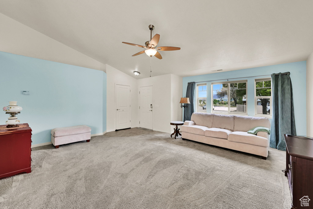 Living room featuring ceiling fan, carpet flooring, baseboards, and lofted ceiling