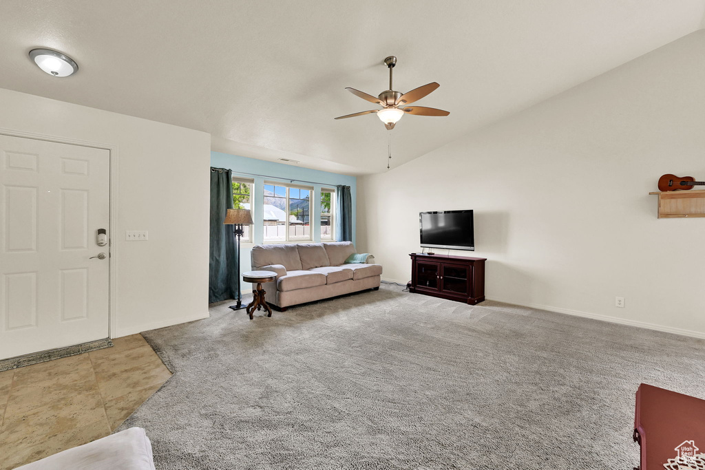 Living room with a ceiling fan, lofted ceiling, and baseboards