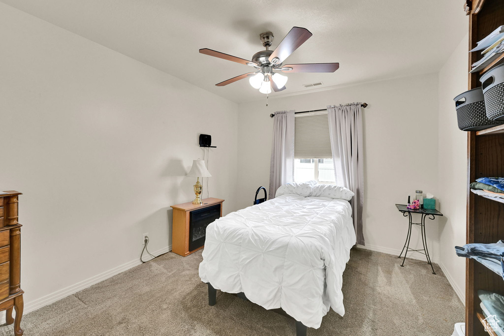 Bedroom with light colored carpet, baseboards, and a ceiling fan