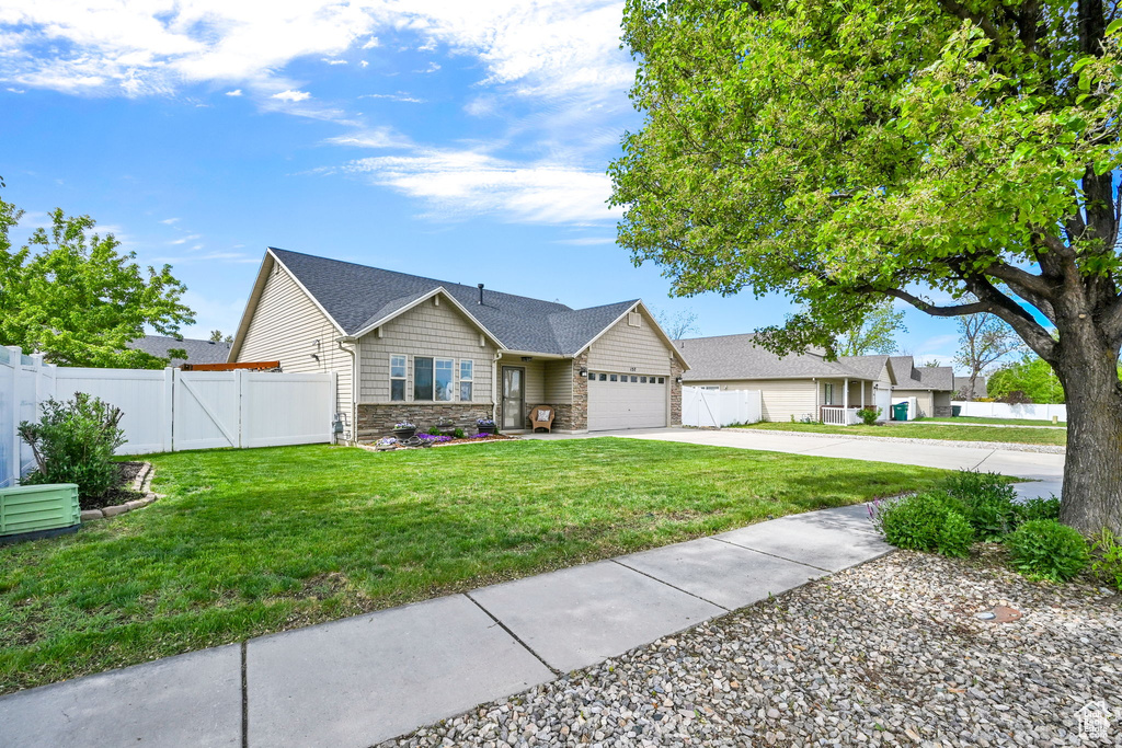Ranch-style house featuring stone siding, an attached garage, driveway, and a gate