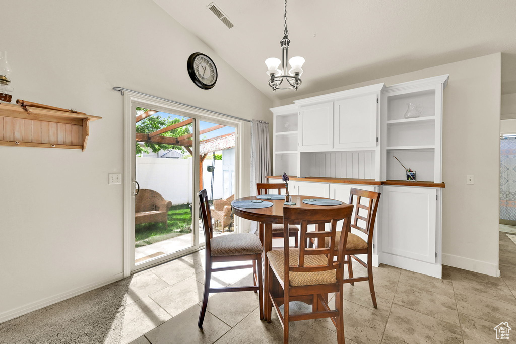 Dining room featuring a chandelier, vaulted ceiling, and baseboards