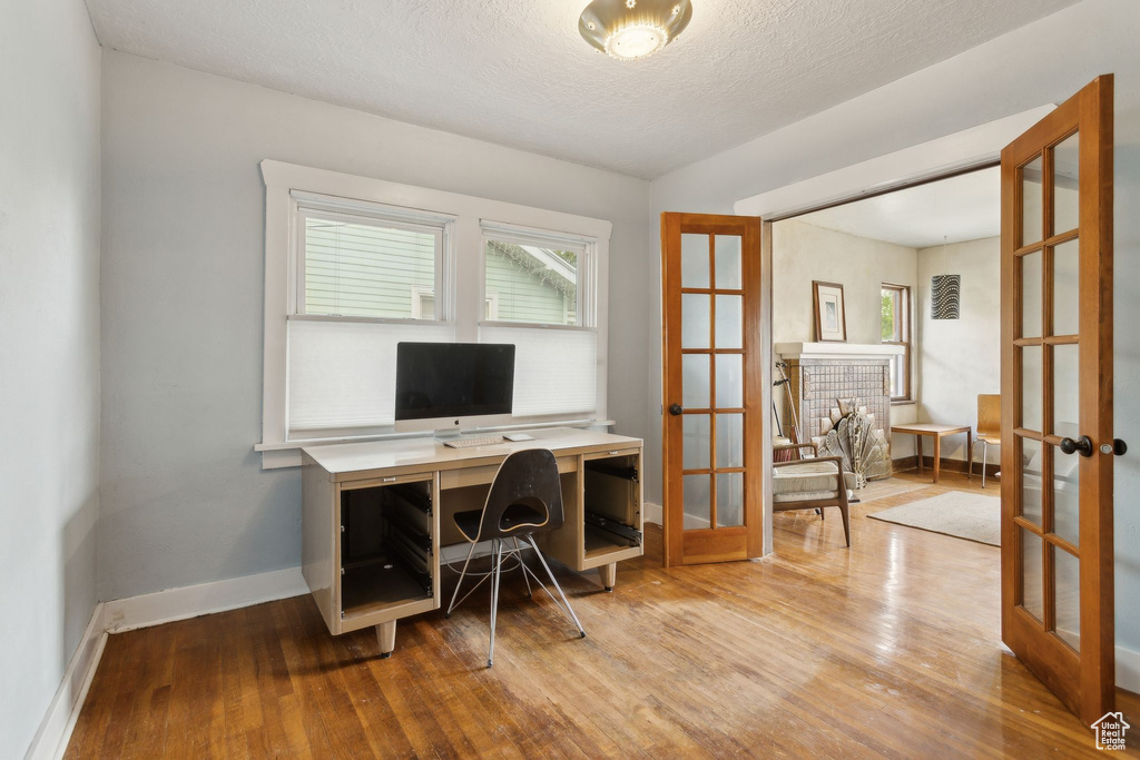 Office space with wood finished floors, french doors, baseboards, and a textured ceiling