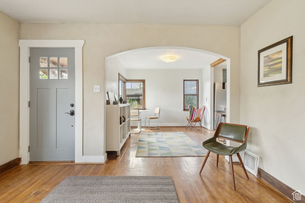 Foyer entrance with arched walkways, baseboards, visible vents, and wood finished floors