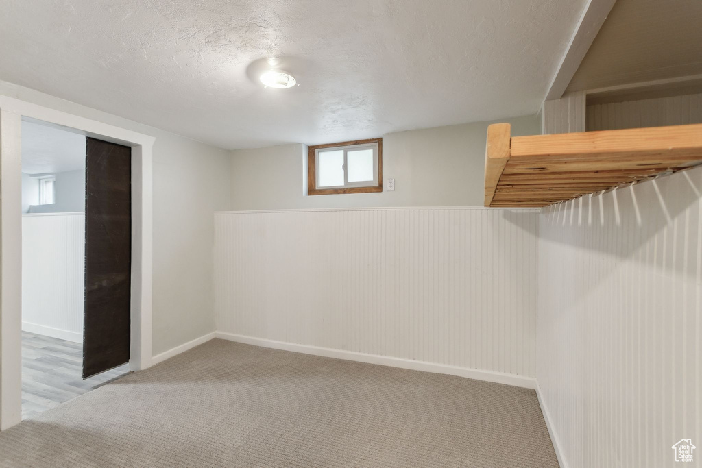 Basement featuring a textured ceiling, carpet, and baseboards