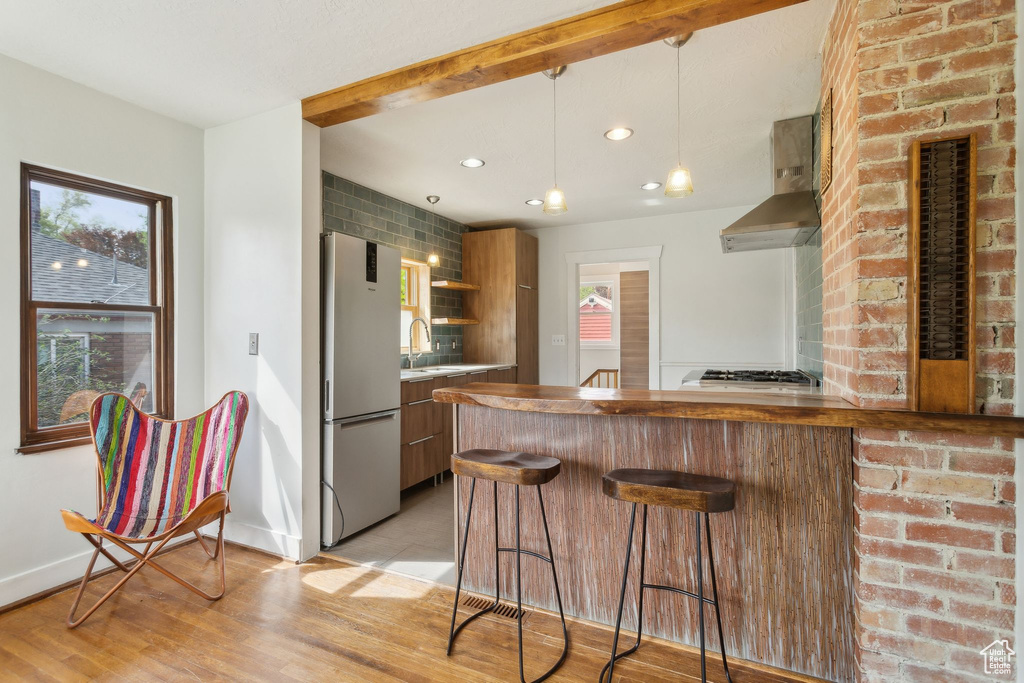 Kitchen featuring plenty of natural light, wall chimney exhaust hood, stainless steel appliances, and modern cabinets