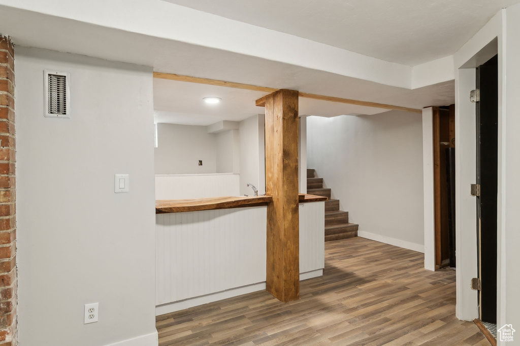 Finished below grade area featuring stairway, baseboards, visible vents, and wood finished floors