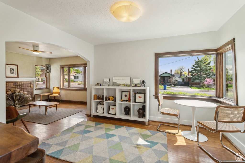 Living area with plenty of natural light, baseboards, wood finished floors, and arched walkways