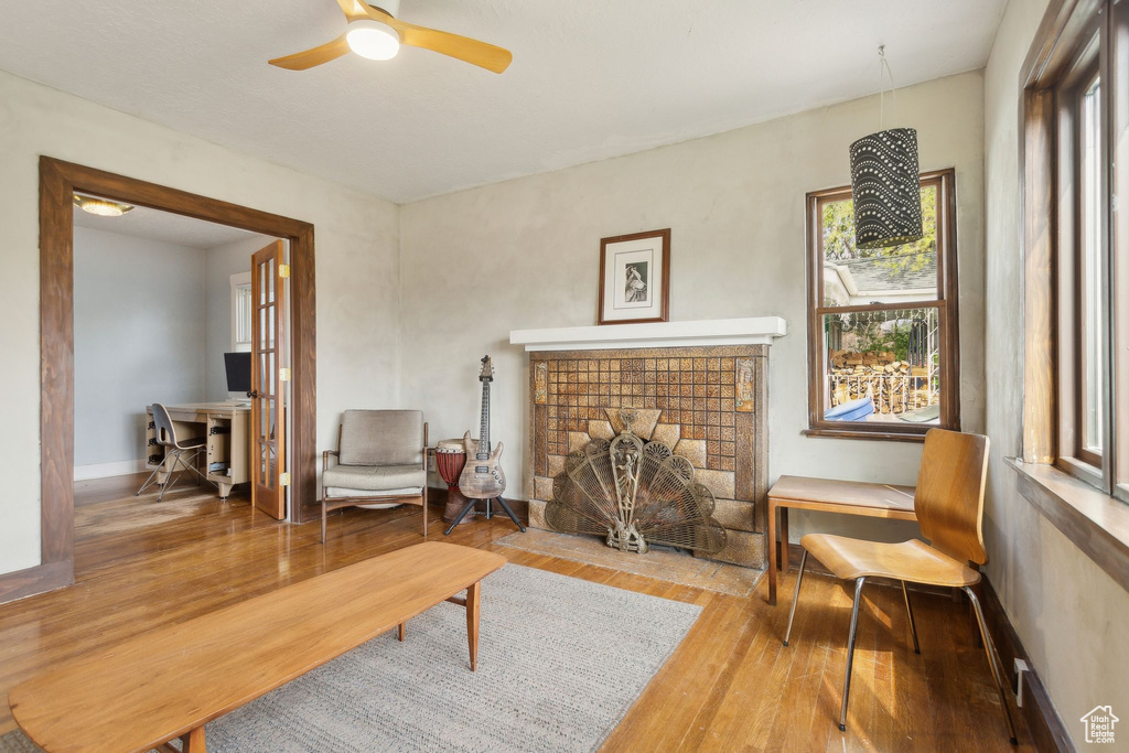 Sitting room featuring a wealth of natural light, a fireplace with flush hearth, a ceiling fan, and wood finished floors