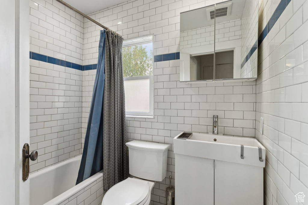 Full bath featuring tile walls, toilet, vanity, visible vents, and tiled shower / bath