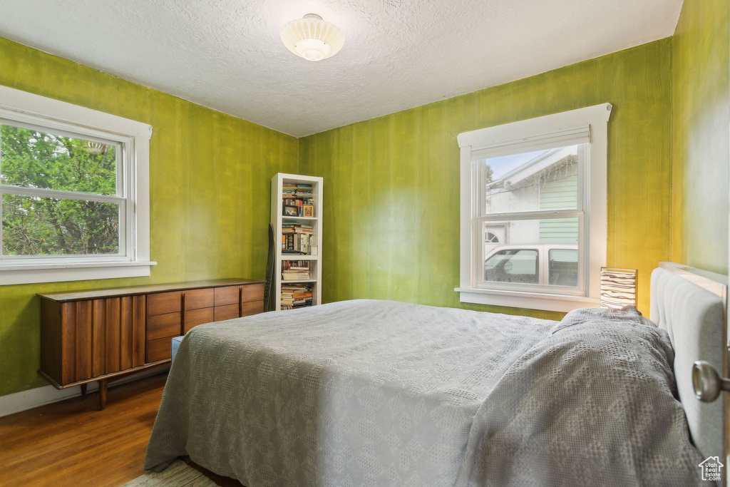 Bedroom featuring a textured ceiling, multiple windows, and dark wood-style floors