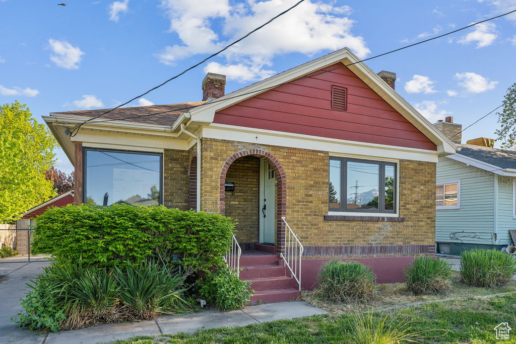 Bungalow with a porch, brick siding, and a chimney