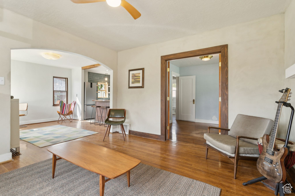 Living area with ceiling fan, wood finished floors, baseboards, and arched walkways