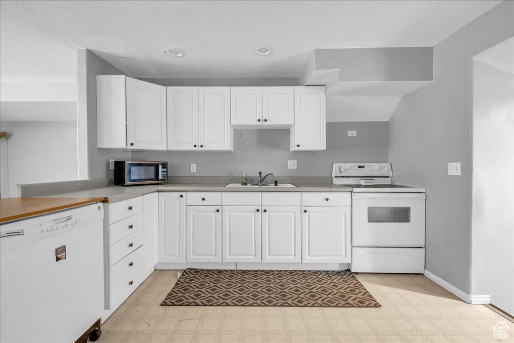 Kitchen with white appliances, a sink, light floors, white cabinetry, and recessed lighting