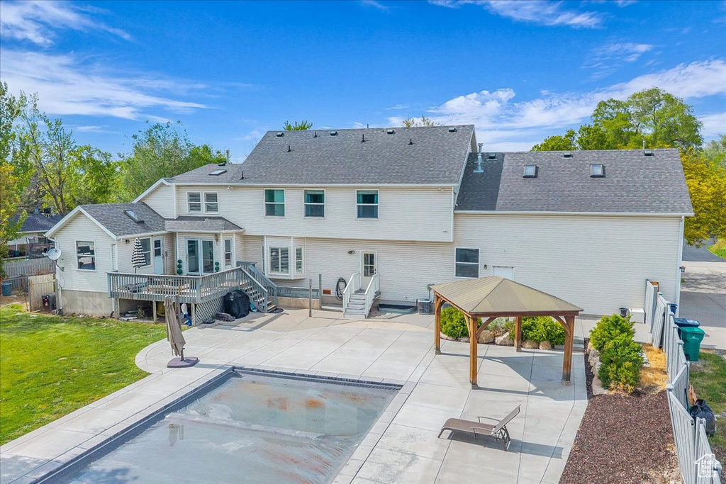 Rear view of property with a gazebo, a deck, a patio, and a shingled roof