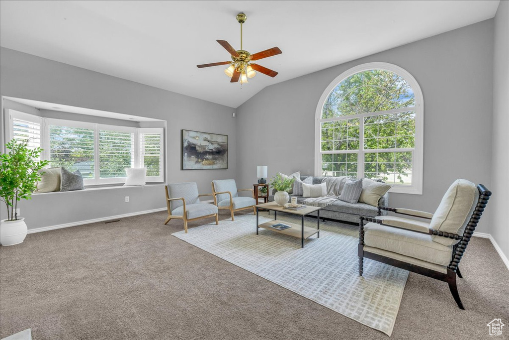 Living room with a ceiling fan, carpet, lofted ceiling, and baseboards