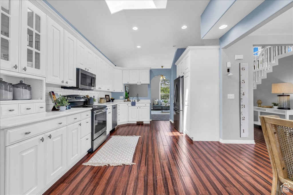 Kitchen featuring appliances with stainless steel finishes, glass insert cabinets, light countertops, white cabinetry, and recessed lighting