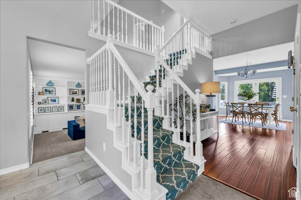 Stairway featuring a chandelier, a towering ceiling, baseboards, and carpet floors