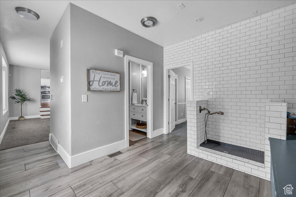 Bathroom featuring a tile shower, wood finished floors, and baseboards