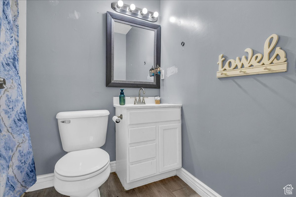 Bathroom with wood finished floors, baseboards, toilet, and vanity