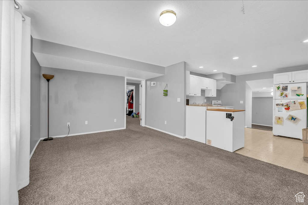 Unfurnished living room with light colored carpet, baseboards, and recessed lighting