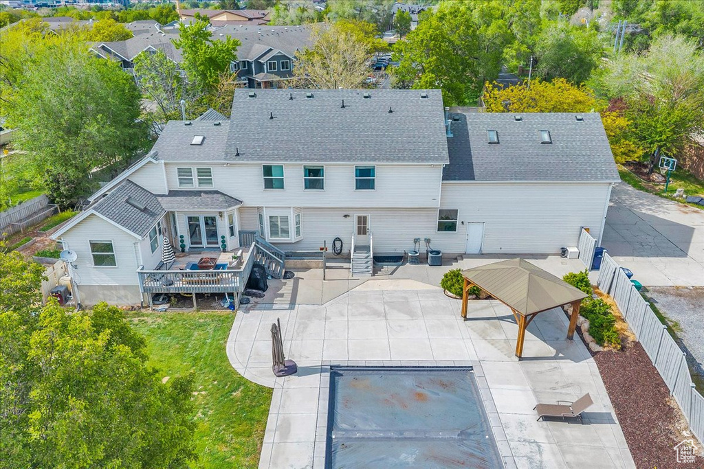 Back of house with a wooden deck, a patio, roof with shingles, and a gazebo