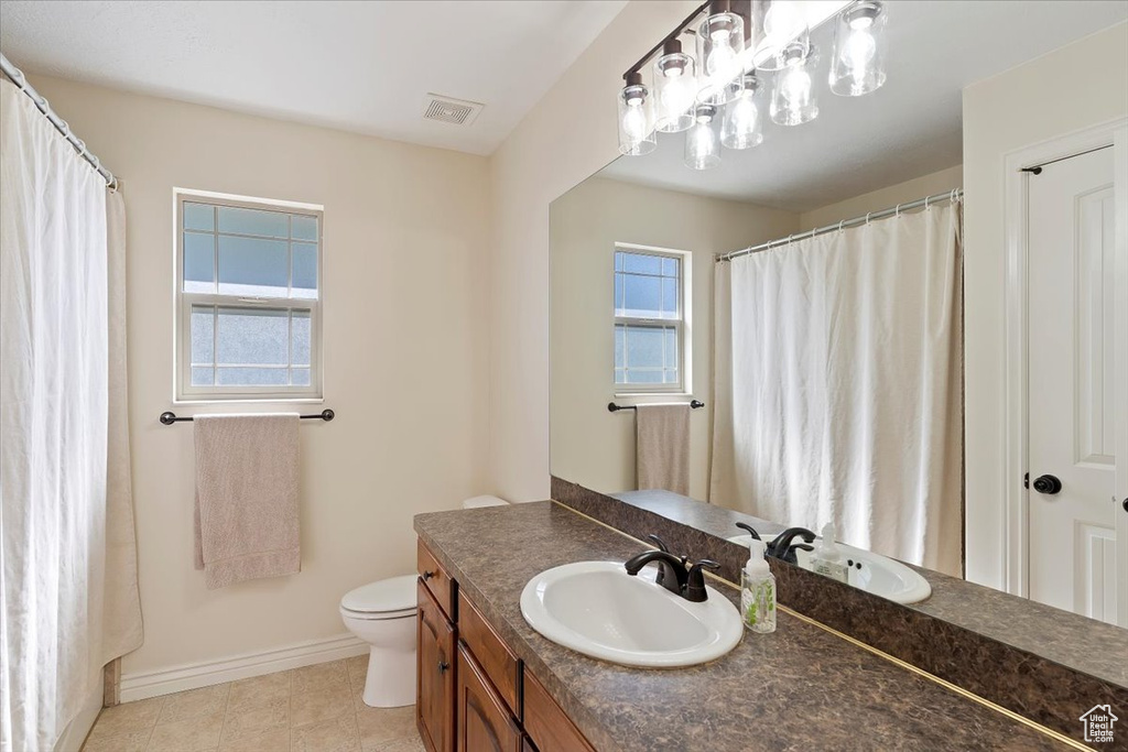 Full bathroom with baseboards, vanity, toilet, and tile patterned flooring