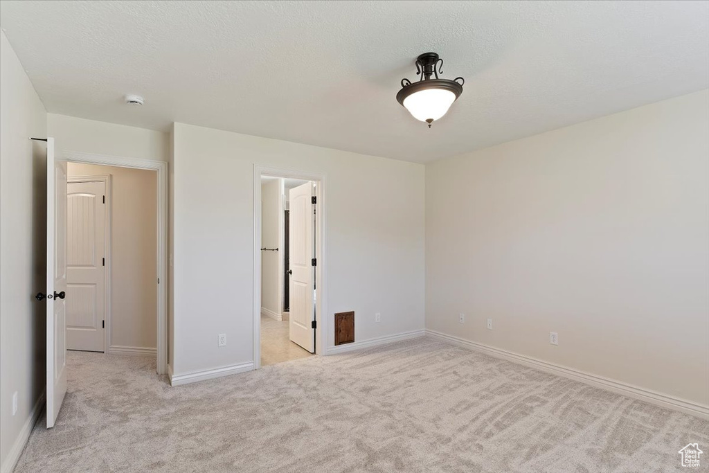 Unfurnished bedroom featuring light colored carpet and baseboards