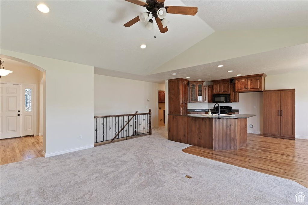 Kitchen featuring black microwave, ceiling fan, recessed lighting, lofted ceiling, and open floor plan