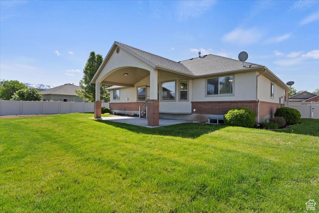 Back of property with brick siding, a patio area, stucco siding, and a shingled roof